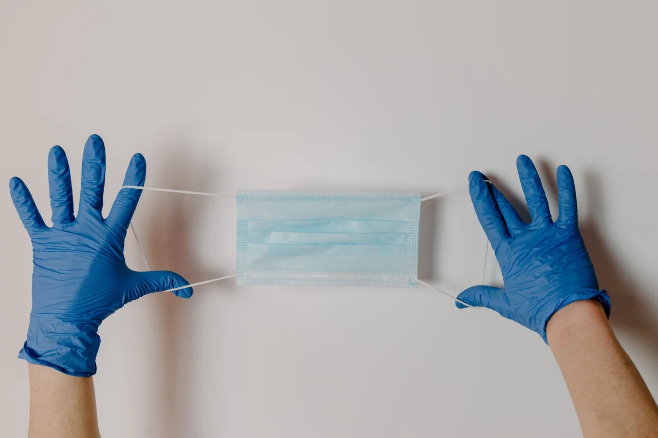 Gloved hands holding a disposable medical mask